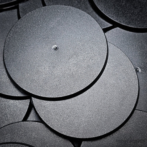 Cluster of 90mm round bases stacked on a black surface, close-up detail.