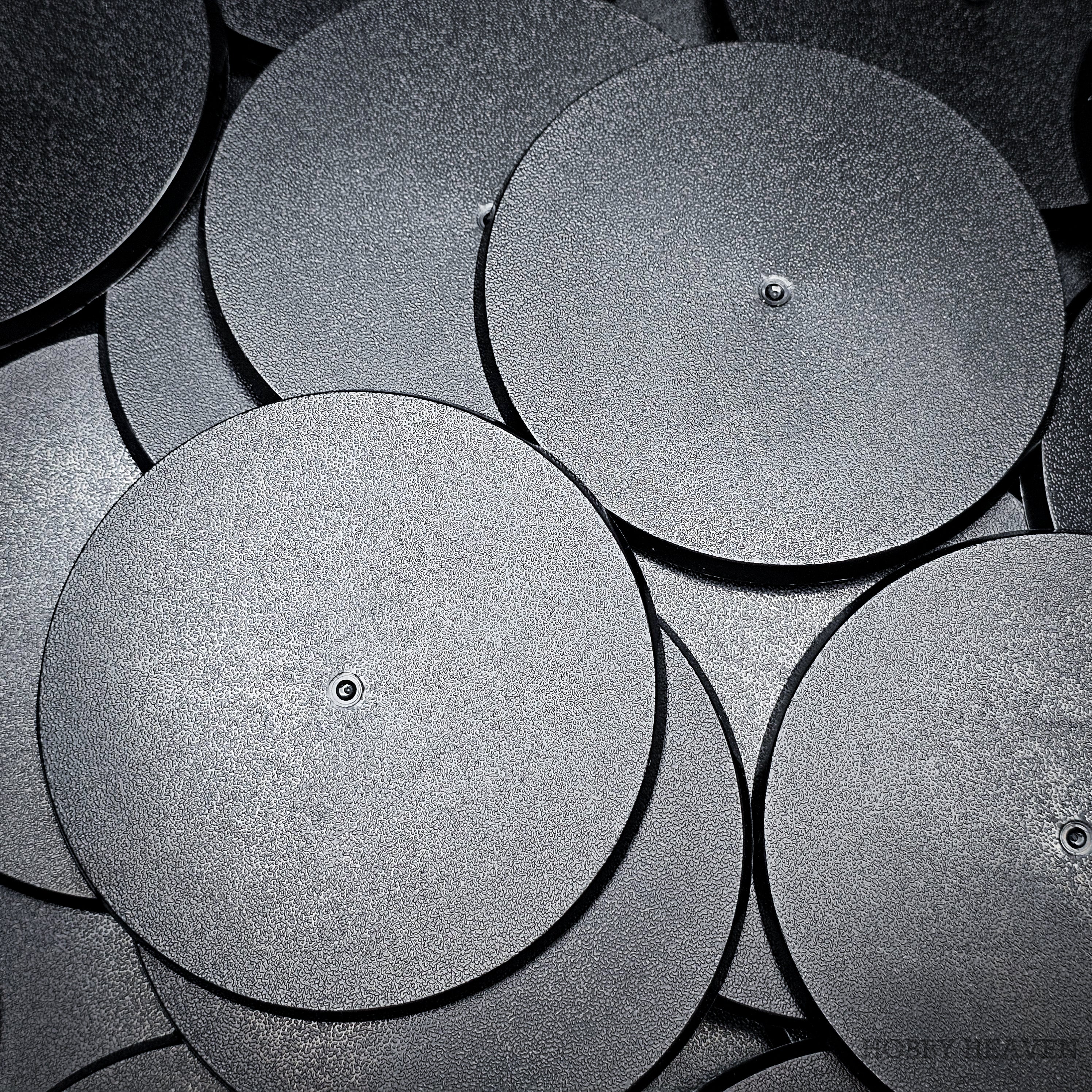 90mm round bases in a group on a black surface, with close-up details.