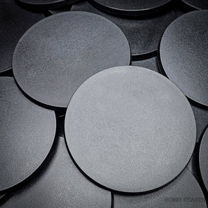 Close-up of clustered 100mm round bases on a dark surface.