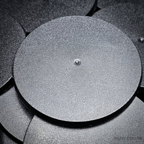 Black 90mm round plain plastic wargaming bases with a fine textured top, injection-moulded ABS, shown in a pile.
