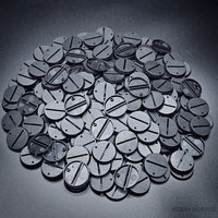 Macro shot of 32mm round slotted bases on a black surface.
