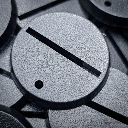 Black 32mm round slotted wargaming bases with a textured top and central slot for tab-mounted miniatures, ABS.