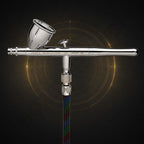 Iwata Revolution CR seen from the front, connected to a braided multicoloured airbrush hose