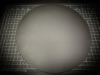 Top-down photograph of the 300mm round smooth PLA base on a cutting mat, showing the clean matte surface with faint concentric FDM layer lines.