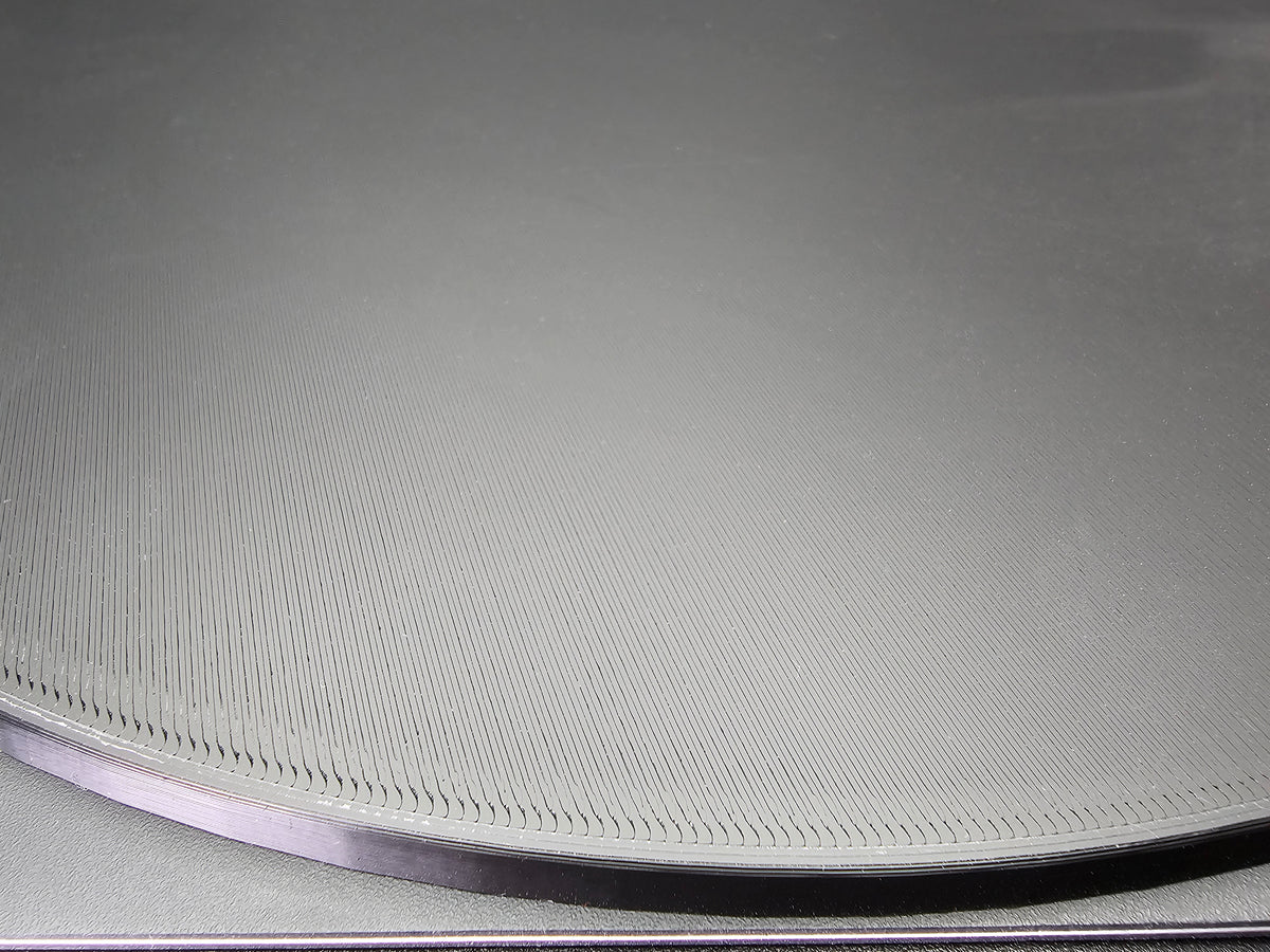 Close-up of the edge of the 300mm round smooth PLA base showing FDM layer lines in detail along the bevelled rim.