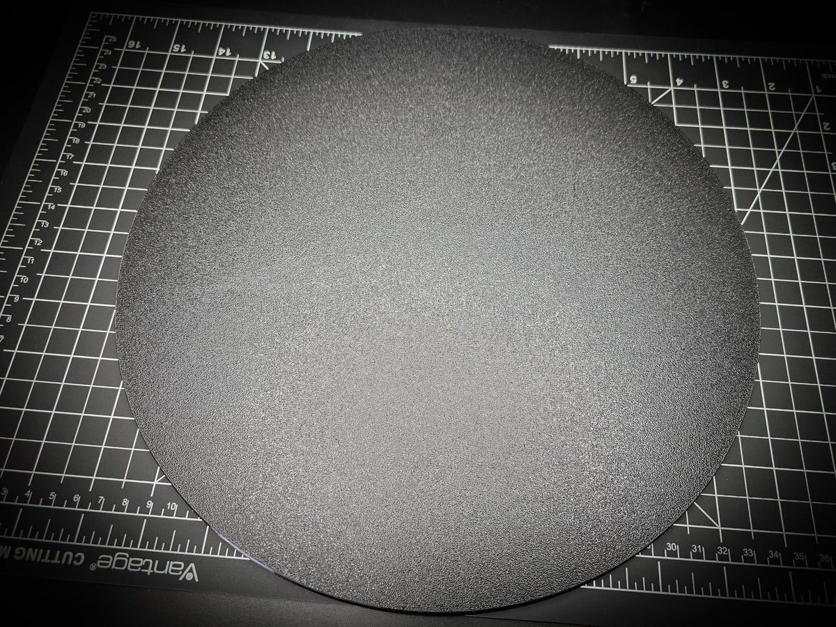 Angled photograph of the 300mm round textured PETG base on a cutting mat, showing the thin 6mm profile and textured surface.