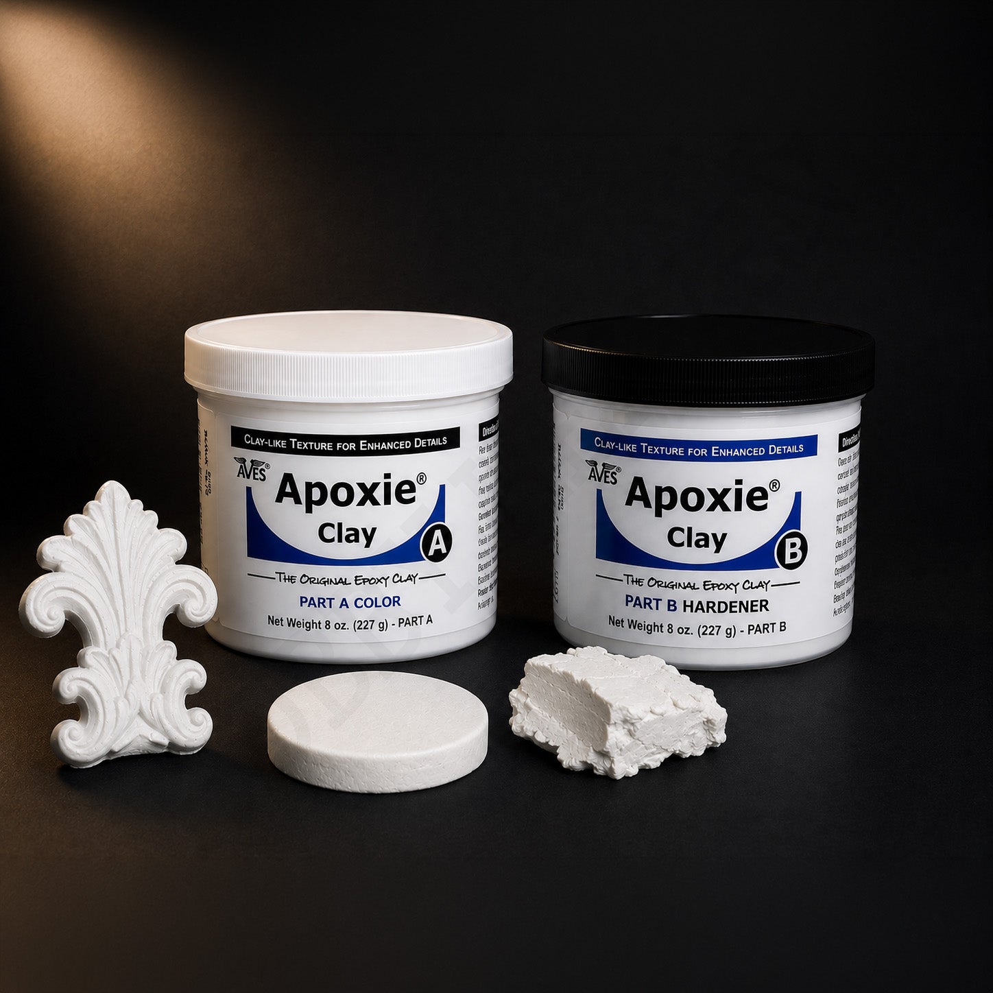 Aves Apoxie Clay Part A colour and Part B hardener jars with a cured white ornament, disc and torn lump
