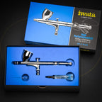 Iwata HP-C Plus in its open blue High Performance Plus box with a tube of Iwata Lube and a slim metal part