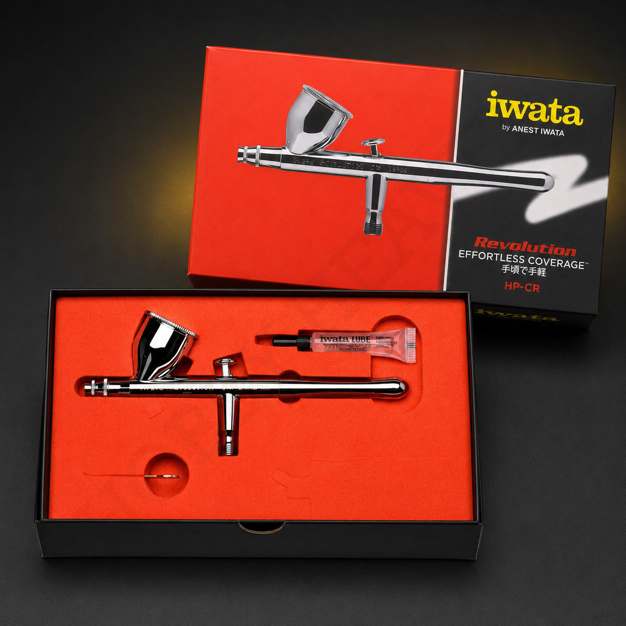 Iwata Revolution CR in its open red presentation box with a tube of Iwata Lube and a slim metal part