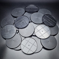 Cluster of 90mm round bases arranged in a pile on a black surface.
