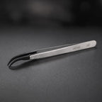 DSPIAE AT-TZ08 anti-static tweezers on dark slate, the black carbon fibre tips curving down to a hooked point