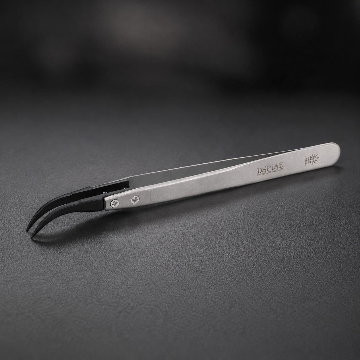 DSPIAE AT-TZ08 anti-static tweezers on dark slate, the black carbon fibre tips curving down to a hooked point