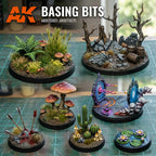 Individual painted miniature bases using AK Interactive Basing Bits on a cutting mat showing forest vegetation, dead tree with ruins and barrels, giant mushrooms with arrows, cacti with candles, sci-fi portal effects, and water lilies display bases 