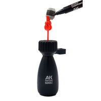 AK Interactive holding pin mounted in AK9565 Handle Support with a small miniature barrel gripped in the clip-top being painted with an AK RCM013 Chipping marker demonstrating practical sub-assembly painting use

