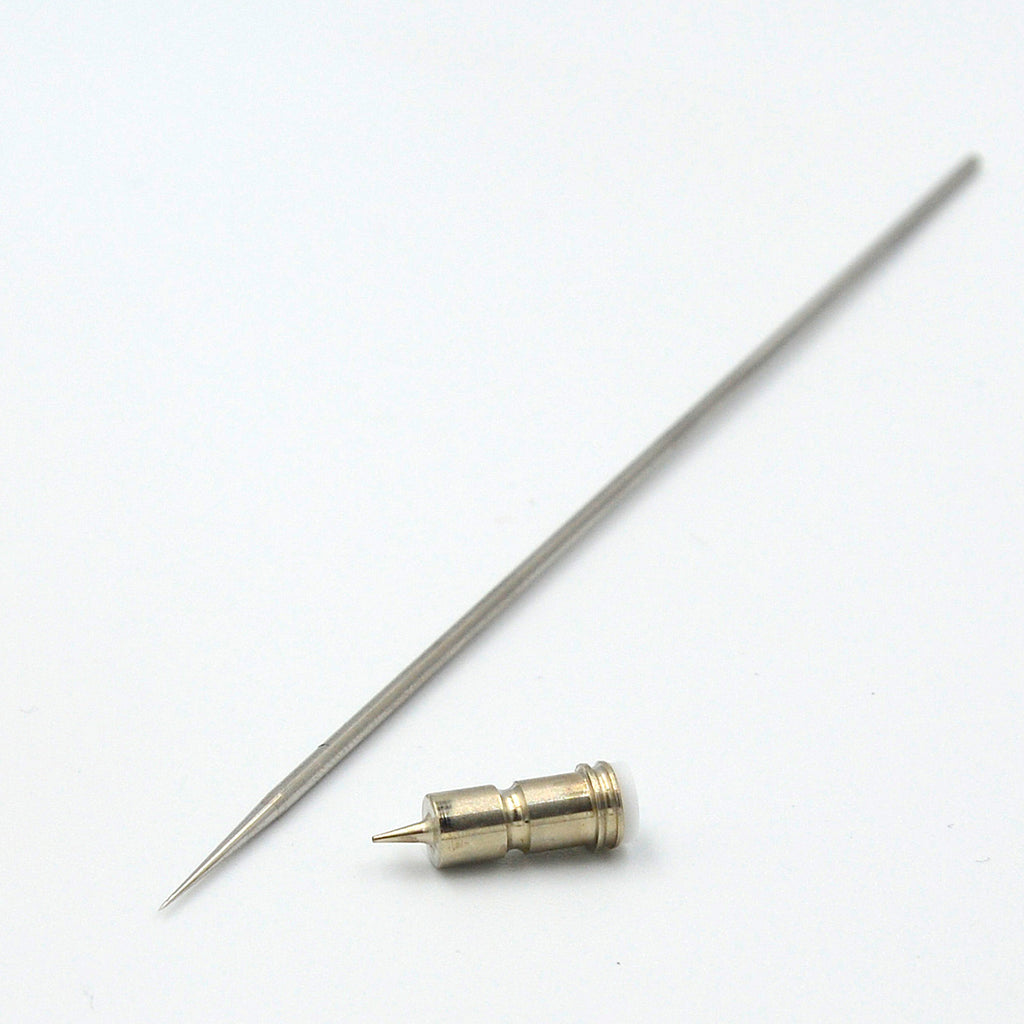 AK Interactive 0.2mm replacement parts showing full-length stainless steel needle with precision-ground taper and brass self-centering nozzle with visible orifice and stepped collar on white background