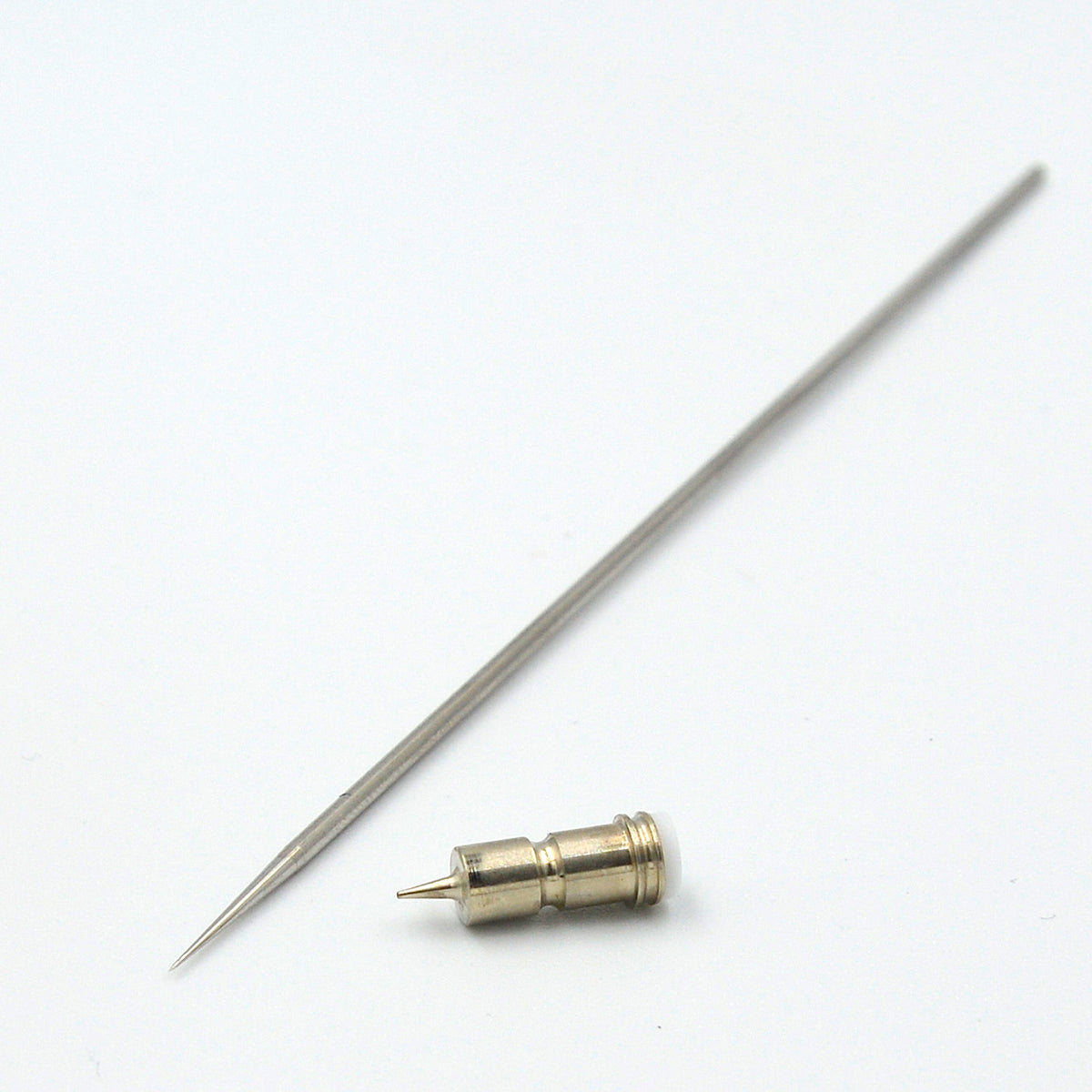 AK Interactive 0.2mm replacement parts showing full-length stainless steel needle with precision-ground taper and brass self-centering nozzle with visible orifice and stepped collar on white background
