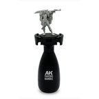 AK Interactive Painting Handle front view with unpainted fantasy warrior miniature mounted on top showing ergonomic black bottle-shaped grip body with AK Painting Handle branding