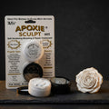 Aves Apoxie Sculpt White 1/4 lb product pack showing the retail blister card, Part A and Part B sample tubs, and a white sculpted rose beside the product