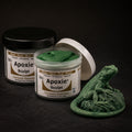 Aves Apoxie Sculpt 1lb Green — Part A tub open showing green putty, Part B tub behind, with a detailed sculpted iguana figure demonstrating the material's fine detail capability