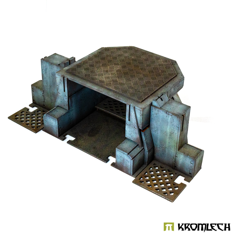 Open back of the blue-grey strongpoint from a rear corner, grated floor plates at both flanks