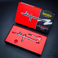 Iwata Revolution BR airbrush in open box with red foam insert and included lube
