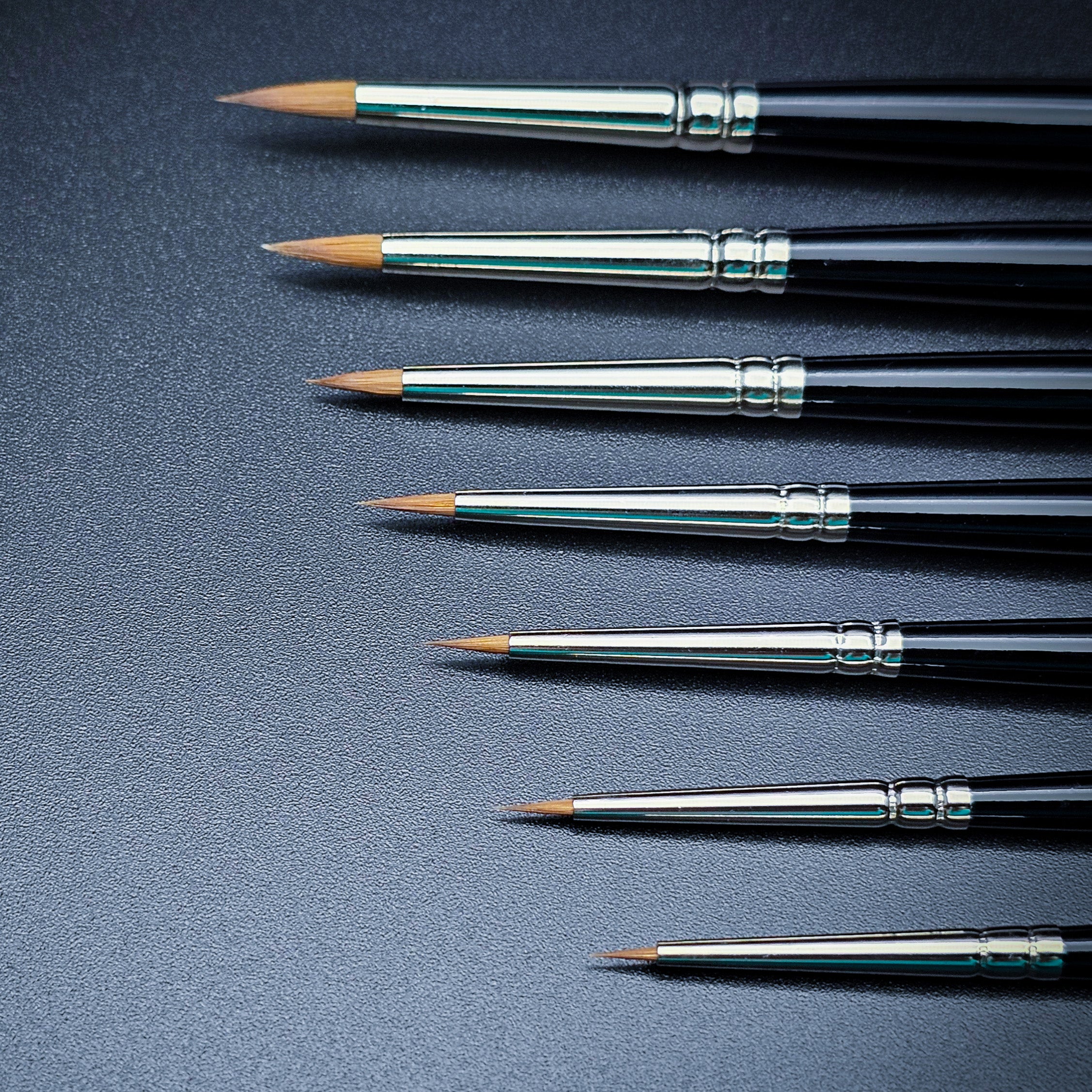 Winsor & Newton Kolinsky Sable Brush set - 7 diverse sizes contrasting on black surface