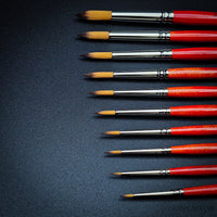 Close-up of Raphael Series 8394 Kaerell round brushes with red handles for fine detail and watercolour painting
