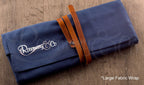 Rosemary & Co large fabric brush wrap shown closed on wooden surface with navy canvas body and leather strap