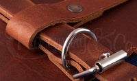 Close-up of Rosemary & Co leather fabric brush wrap showing tan leather strap, metal buckle and stitched leather detail
