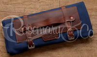 Rosemary & Co short handle leather fabric brush wrap shown closed on wooden surface with navy canvas body and tan leather fittings
