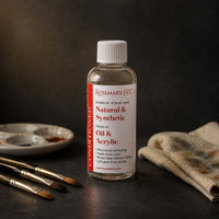 Rosemary & Co brush cleaner 100ml on a dark studio bench with sable brushes, ceramic palette and a paint-stained cloth
