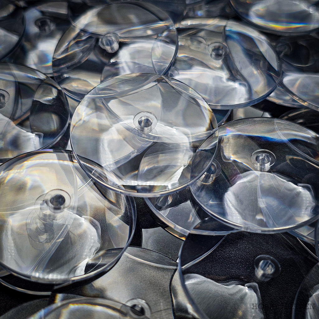 Close-up of 32mm PS plastic clear base showing scratch-resistant surface and exceptional clarity compared to standard acrylic