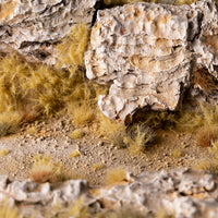 Realistic Mediterranean diorama featuring Spikey Beige 12mm - Wild Tufts, showcasing a diverse landscape with thorny shrubs, dry vegetation patches, and rugged terrain, demonstrating the product's effectiveness in creating authentic scrubland environments
