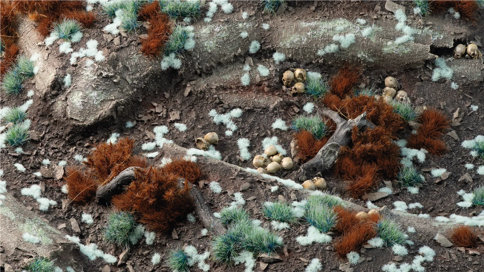 Gamers Grass Tiny Pale Teal 1mm tufts scattered on dark earth diorama terrain with contrasting brown tufts and woodland debris
