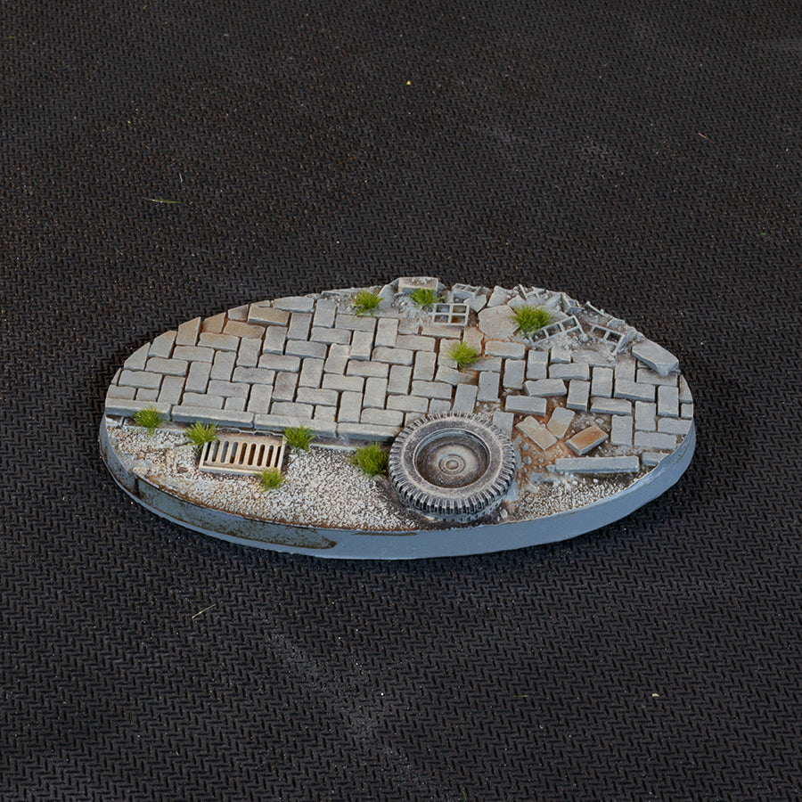 Brick paving, a drain grate and a discarded tyre in gravel, on a 90 mm Urban Warfare oval base