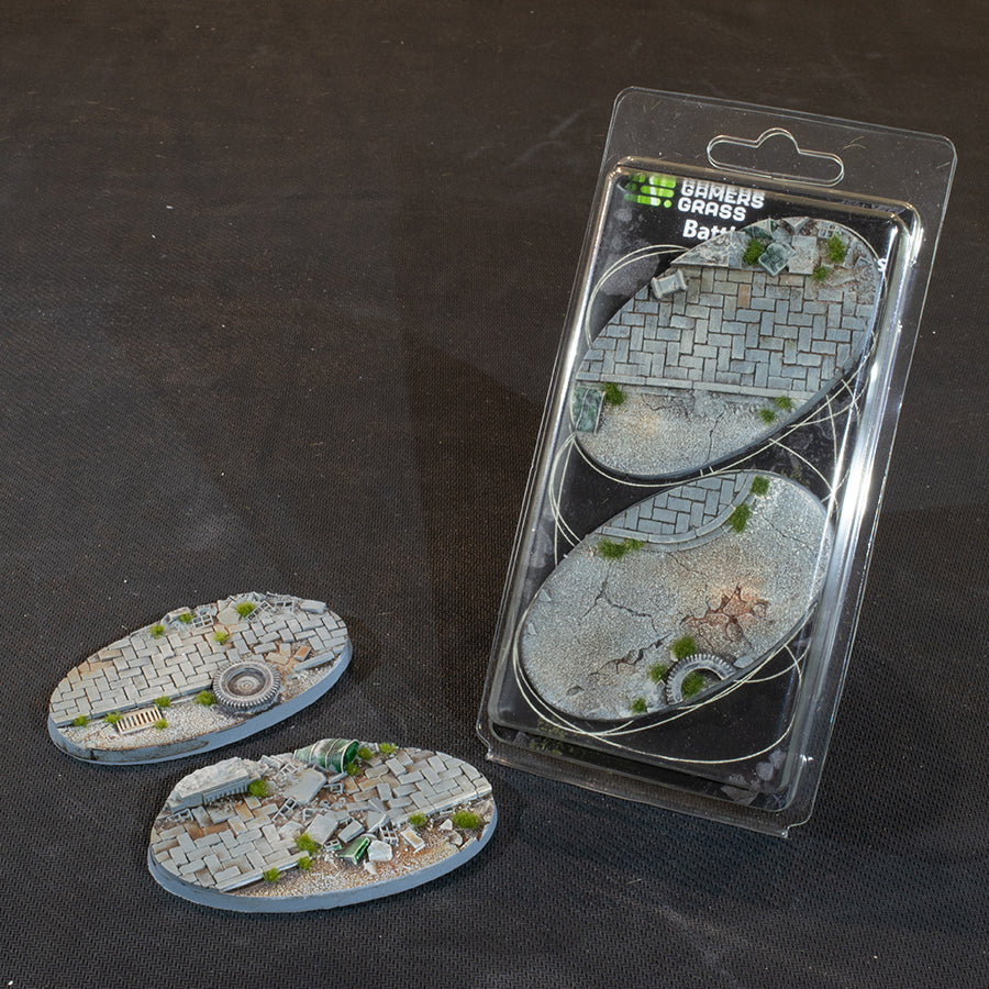 Two Urban Warfare 90 mm oval bases beside the Gamers Grass blister, both with ruined street surfaces