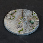 The 100mm base seen from above: a band of gravel dividing two stretches of paving, drum and crate among the debris