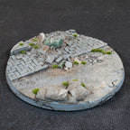 Urban Warfare 100mm base: brick paving and a green fuel drum on its side, with sandbags on open grit in front
